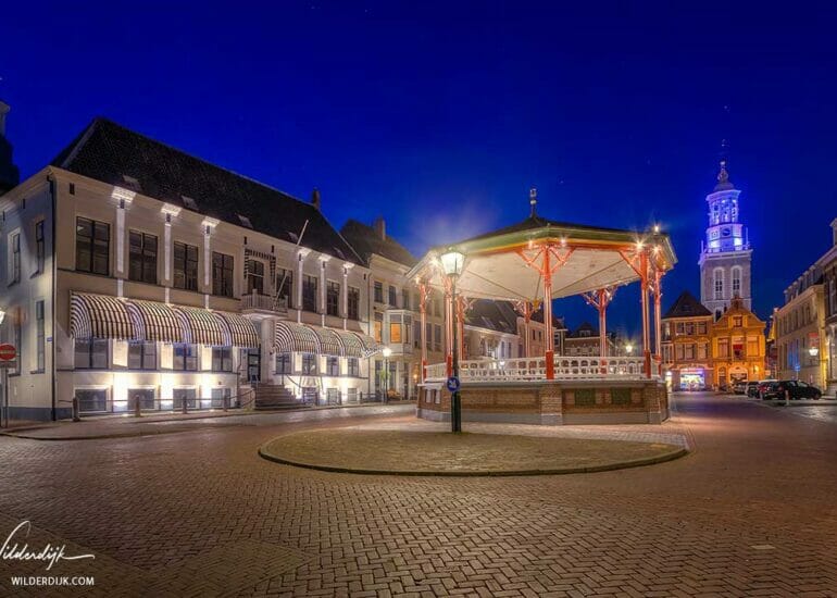 De verlichte Nieuwe Markt in Kampen tijdens het blauwe uur na zonsondergang