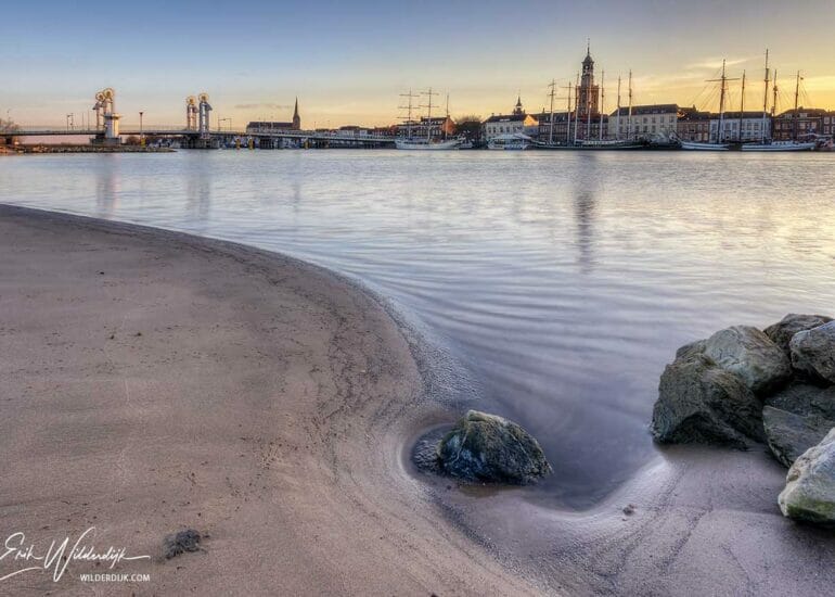Het stadsfront van Kampen met stenen op de voorgrond bij zonsondergang