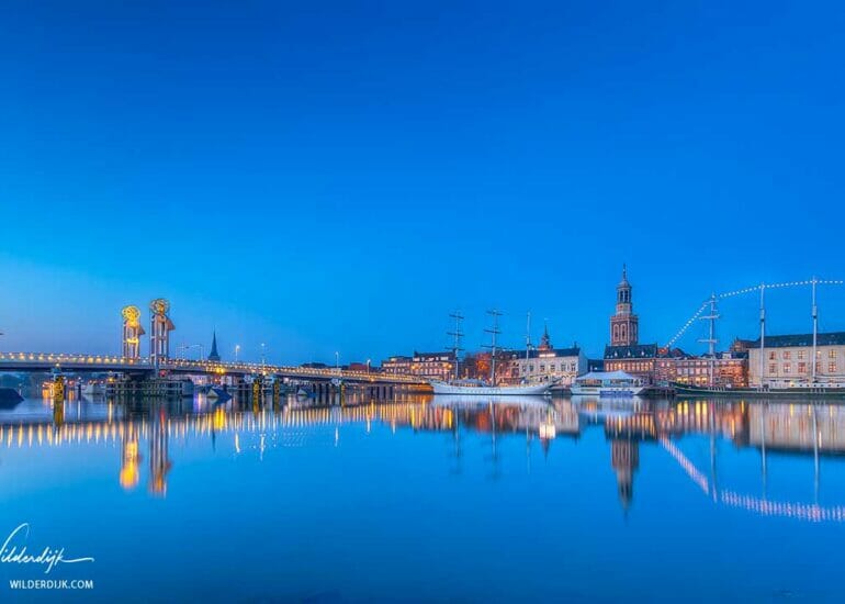Het stadsfront van Kampen bij zonsopkomst en een strakblauwe lucht weerspiegelnd in het water van de IJssel