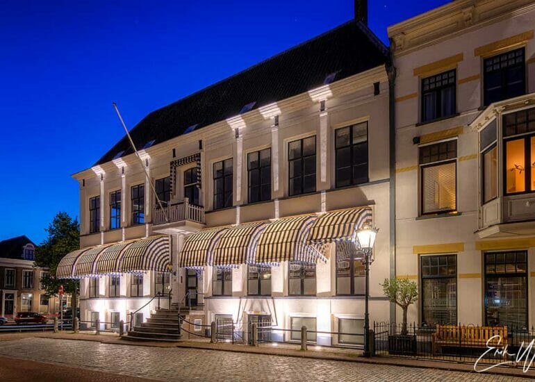 Het aangelichte voormalig militair tehuis aan de Nieuwe Markt in Kampen bij avond