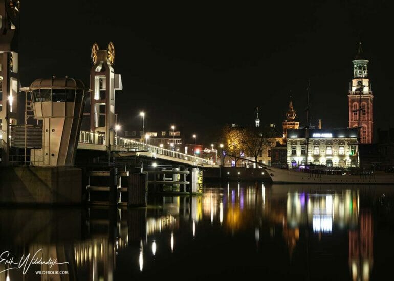 Stadsbrug en Nieuwe Toren, onderdeel van het stadsfront van Kampen, aangelicht in contrast met de zwarte kleur van de nacht