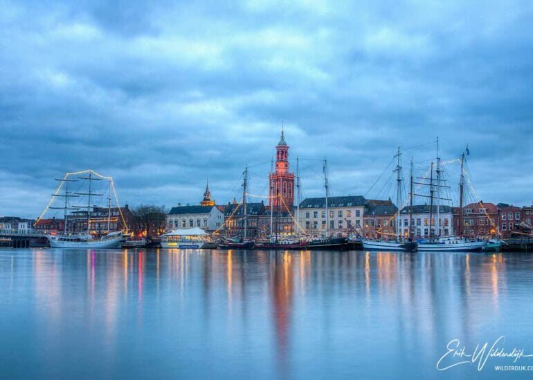 Een oranje aangelichte Nieuwe Toren in het aangezicht van het stadsfront van Kampen tijdens de campagne Color The World